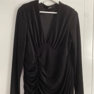 Svart Klänning - En svart V ringad Klänning i storlek (L) rekommenderas också för (M) från Bik bok. Material: Polyester och Elastan. Klänningen har använts Max 1 gång. 