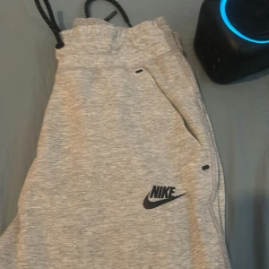 Nike tech byxor - Grå Nike tech byxa, knappt använd. Säljs då den e för liten på mig. Bra skick! Ser ut å va nya☺️