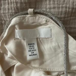 Festlig topp - Festlig topp ifrån hm som aldig har använts. Den har glittriga detaljer och är i satin. Den är i storlek XS men passar även S och M. Den är beige💕