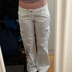 Vita byxor  - Vita, låga, cargobyxor med broderade blommönster, de är ganska långa på mig som är ca 167cm. 💗
