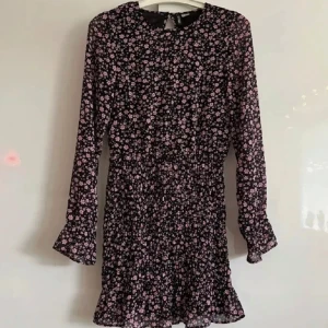 Blommig klänning - En svart klänning med lila/rosa blommor med volang nedtill samt vid ärmslut från H&M i strl XS!💓