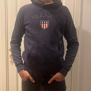 Gant hoodie  - Marinblå gant hoodie. Skick 7/10 lite slitage på armbågarna. Storleken är 176 cm eller 16 år, passar S. Modellen är 182 cm.