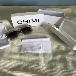 Säljer Chimi solglasögon, modell 05. Grå med mörka linser, nästan nya, endast använda några få gånger. Medföljer: originalfodral, putsduk och förvaringspåse. Perfekta för att ge din sommarstil ett lyft. Skydda ögonen med stil!   Pris kan diskuteras