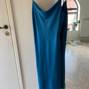 Marin blå satin klänning - Säljer denna midi/maxi klänning från frakment i Köpenhamn. Helt oanvänd, nyskick utan prislapp! Formar sig otroligt efter kroppen. Köpt för ca 800-900kr. Super fin som balklänning! Faller jätte fin på kroppen och formar vackert.