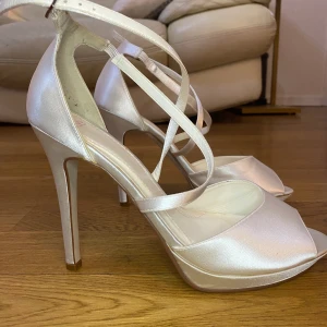 Klackskor  - Jättefina klackskor perfekt till bröllop eller annat festligt tillfälle. Använda fåtal gånger. Klackarna är ca 10 cm höga. Jättefint tyg i siden.