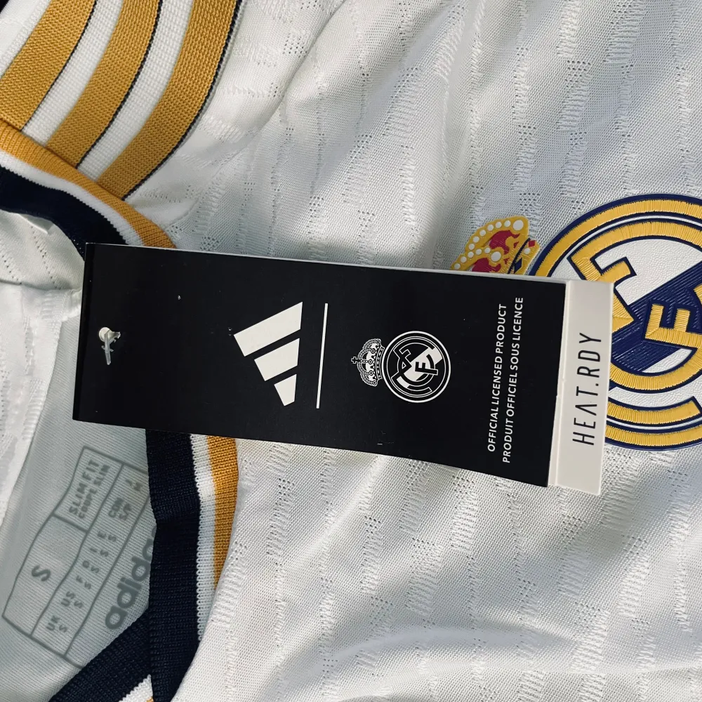 Real Madrid Hemmatröja 2023/2024  Säljer en ny Real Madrid hemmatröja för säsongen 2023/2024. Vit med guld- och mörkblå detaljer. Klubbmärke och Adidas. T-shirts.