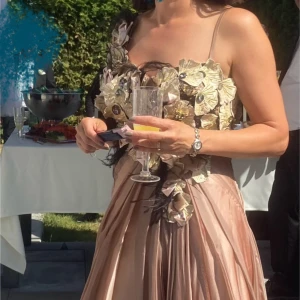 Hellång vacker festklänning  - Vacker hellång chiffongklänning med blommor upptill. Storlek 36. Jag är 160 med klack på bilden .Färgen är en skimrande makeup färg , åt det beiga hållet.