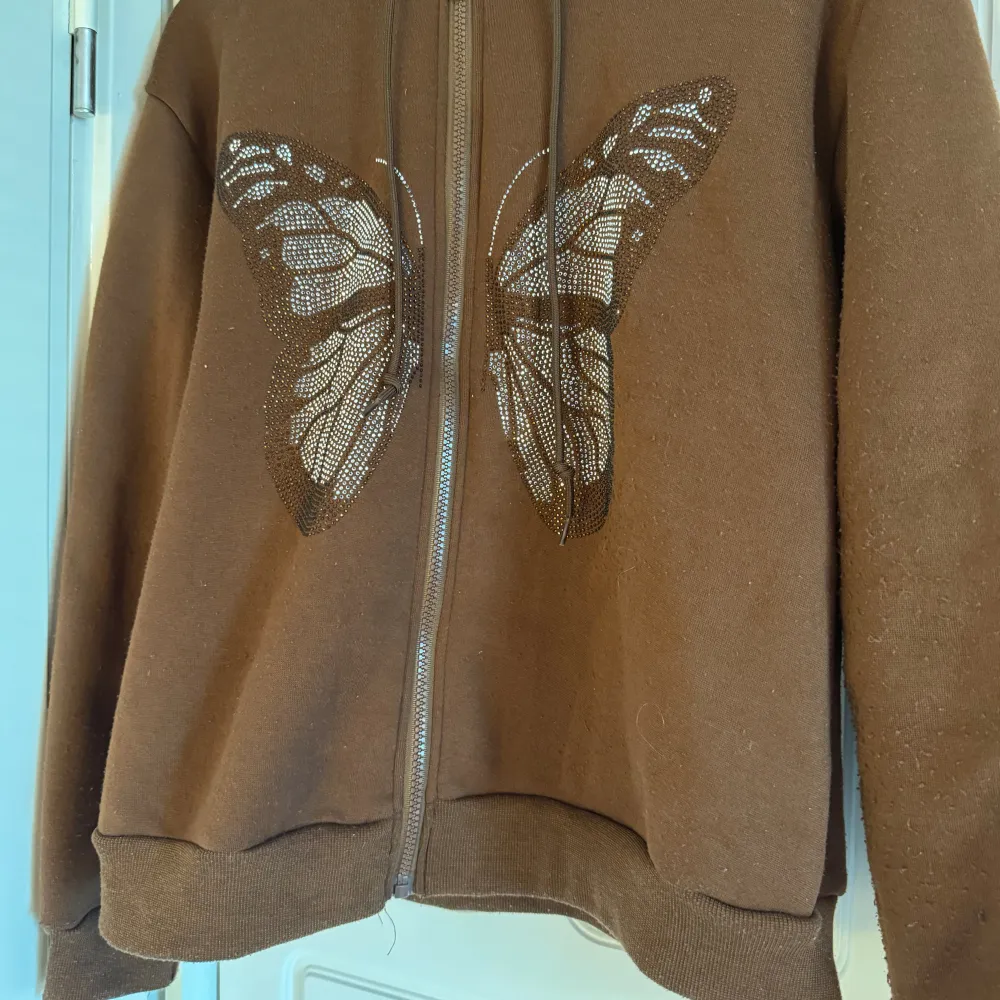 Brun zip up hoodie med fjäril. Hoodies.