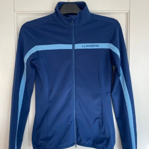 J.Lindeberg mid layer - träningsjacka  - Storlek: S Säljer min träningsjacka från J.Lindeberg  Köptes i början av 2024 Nypris: 1300 kr Används 4-5 gånger  Säljer pga sitter lite tajt på mig Dm vid frågor eller specifika bilder  
