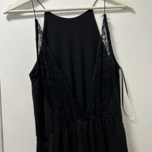 Miniklänning med öppen rygg - Svart lår-lång klänning med tunna axelband och öppen rygg med spetsdetaljer
