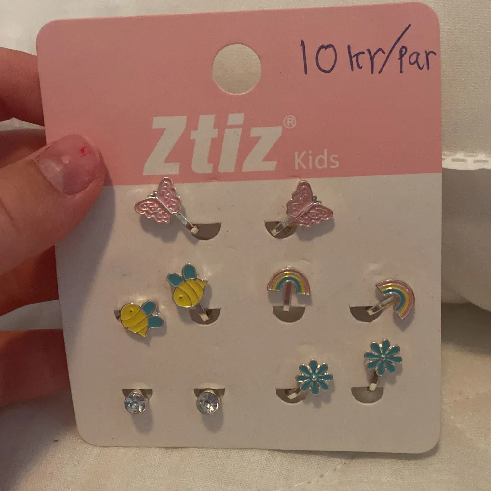 Ett set med sex par örhängen från Ztiz Kids. Örhängena har olika former och färger, inklusive fjärilar, bin, regnbågar, blommor och stenar.. Accessoarer.