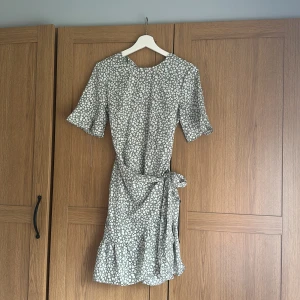 Grön klänning med vita blommor  - Grön klänning med vita blommor från Vero Moda, använd 1-2 gånger, nyskick!  Storlek S