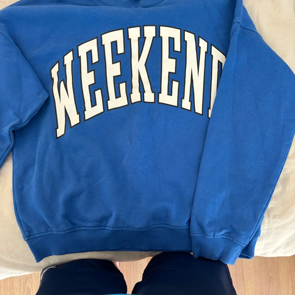 En bekväm blå sweatshirt med texten 'WEEKEND' i vita bokstäver på framsidan. Tröjan har långa ärmar och ribbstickade muddar vid ärmslut och nederkant. Skulle säga att den passar någon som har xs också 💕. Tröjor & Koftor.