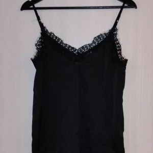 Svart linne med spets. - Fint svart linne bara använd 1 gång, skönt siden material, spets uppe vid kanterna. 