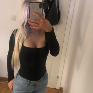 Body med korsett - Jättesnygg svart body med korsett mönster. Sitter jättesnyggt och superbra basic tröja. Aldrig använd. Från fashionnova i storlek xs. Bodysuiten är string där bak.