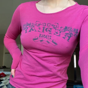 Långärmad Replay tröja - Långärmad mörkrosa/lila tröja med tryck från Replay. SÅ skön men tyvärr används den för sällan. Lappen i nacken har lossnat på ena sidan (se bild 3) men det är inget som direkt syns och borde gå att sy ihop! 