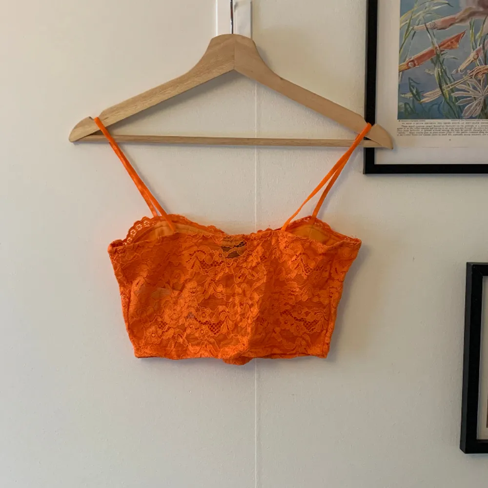 Ett korsett-liknande linne i spets och en stark orange färg. Toppen är endast använd en gång och i mycket bra skick!. Toppar.