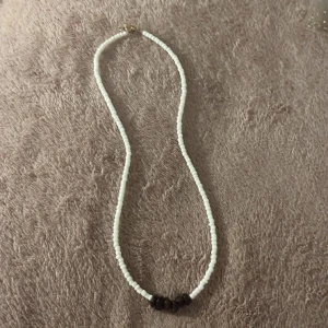 Halsband med kristallstenar - Egengjort halsband med små kristaller och pärlor i sten. Guld knäppe.