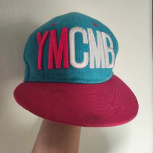 En blå/rosa YMCMB keps, köpt på Second Hand och aldrig använt! Du kan anpassa storleken på den, men passar nog inte ett barn