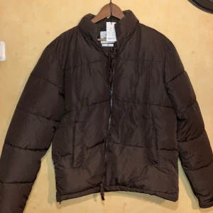 Brun jacka - Varm jacka med krage, går att justera längst ner med band för en mer baggy look. Lik north face i passform. Helt ny Är st S men skulle mer säga M