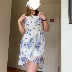 Vit klänning med blått mönster  - Vit klänning med blåa blommor och fjärilar på🦋. Passar bra till skolavslutning eller midsommar. Strl 158 men passar XS-S. 🤗 Skönt material. Använd några få gånger. Skriv för fler bilder😇 