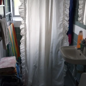 Duschdraperi med volanger och omtag. - En längd duschdraperi med omtag mönstrad blommor och volang på båda sidorna..material Polyester .