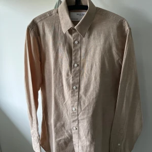 *OANVÄND*Beige linneskjorta från Selected Homme - Säljer en helt oanvänd och ny linneskjorta från Selected Homme, storleken är S men kan passa dig som bär M också. Perfekt nu till sommaren.