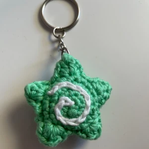 Stjärnnyckelring med swirldetail - Handvirkad nyckelring med gullig swirl detalj<3 Kan göras i flera färger, skriv privat! Gjord av 100% bomullsgarn. Mått: 4,5 x 4,5 cm