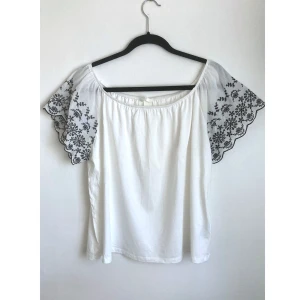 Vit & svart singoalla blus, stl L, bomull, broderi, spets, bohemisk, boho - Vit singoallablus med svarta broderier på ärmarna. Mått i cm: bröstvidd 66; längd fram från axeln 52; ärmlängd 21.