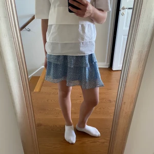 Blå volangkjol - Fin blå volangkjol. Använd en gång, i nyskick och har inga defekter. Går att välja om man vill bära den hög/ mid/ låg midjan i och med att man kan vika upp/ ner resåren. Nypris 600kr. Märket Chelsea. 