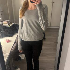 En vanlig grå sweatshirt som har vita pärlor nedtill ärmarna