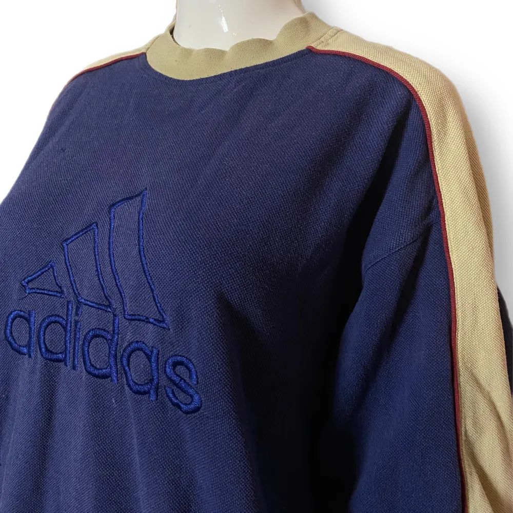 En sweatshirt i engelsk storlek 38/40 från Adidas. Skicket är 7/10 för sin ålder. Finns några slitningar på framsidan. Röda ränder längs ärmarna, syns på sista bilden. Lite mer mörkblå i verkligheten än vad det ser ut som på första bilden. . Hoodies.