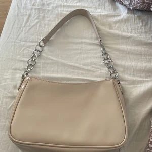 Handväska  - Beige handväska med silver detaljer på bandet. Använd 1 gång 