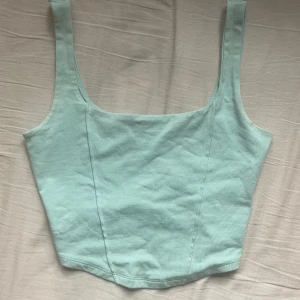 Melody tanktop  - Ett blått croppat linne från Gina Tricot, med sydda veckdetaljer fram. Orginalpris 129 kr.