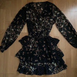Blommig volangklänning  - Långärmad volanggklänning i blommigt mönster från Gina Tricot. 