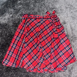 Rutig Kjol - Röd rutig kjol. Den har ett rött band som går att ta av samt justera midjan som enl skärp. Väldigt julig. Perfekt i jultid.