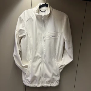 Helt Hansen jacka - Tunn fin vit jacka från Helly Hansens damkollektion. Normal i storleken, även lite stretch i tyget. Bra längd på armarna, även för mig som är 175cm.  Fint skick, endast en lite fläck på armen som säkert går att ta bort men jag har inte testat.  