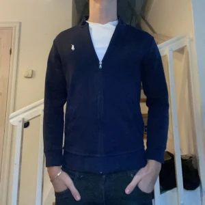Ralph Lauren Zip - Säljer min Hel Zip från Ralph Lauren då den är för liten. Endast använd fåtal gånger. Litet märke under bröstet som kan ses i bild 4. Storlek M herr men sitter mer som S. Skriv vid intresse eller frågor✅