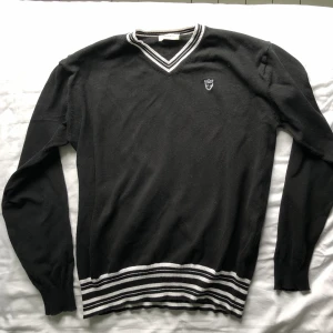 Snygg svart sweatshirt - Snygg klassisk svart sweater med ränder och resår vid ärmarna och slutet av tröjan så att den sitter riktigt snyggt! Den är i mycket bra skick, har nästan alldrig använt.