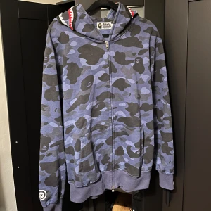 Bape Hoodie - Hej säljer denna fina bape hoodien som använts nån gång, jag säljer den då de inte är min stil längre. Hoodien är en r3,p men ser identisk ut med den vanliga. Tröjan köptes för 1100kr och är i storlek M. Skriv gärna vid frågor eller fler bilder