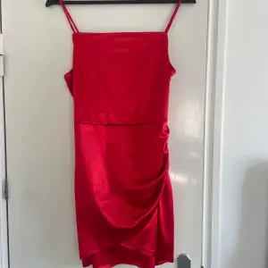Fin röd klänning i ett glansigt material men stretchigt Dragkedja på sidan Har ingen lapp kvar men skulle säga att det är storlek S/M