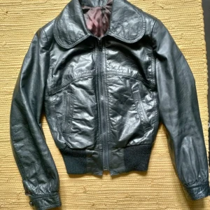 Malung 70 tals jacka vintage mc läder - Malung Leather Jacka Läder 70 tal Snygg malung jacka i kort modell!  Svart skinn. En liten repa på innsidan under kragen.  Dock inget synligt när du har den på.    Armpit:40  Sleeve: 54  Collar to buttom: 58  Shoulders: 36 