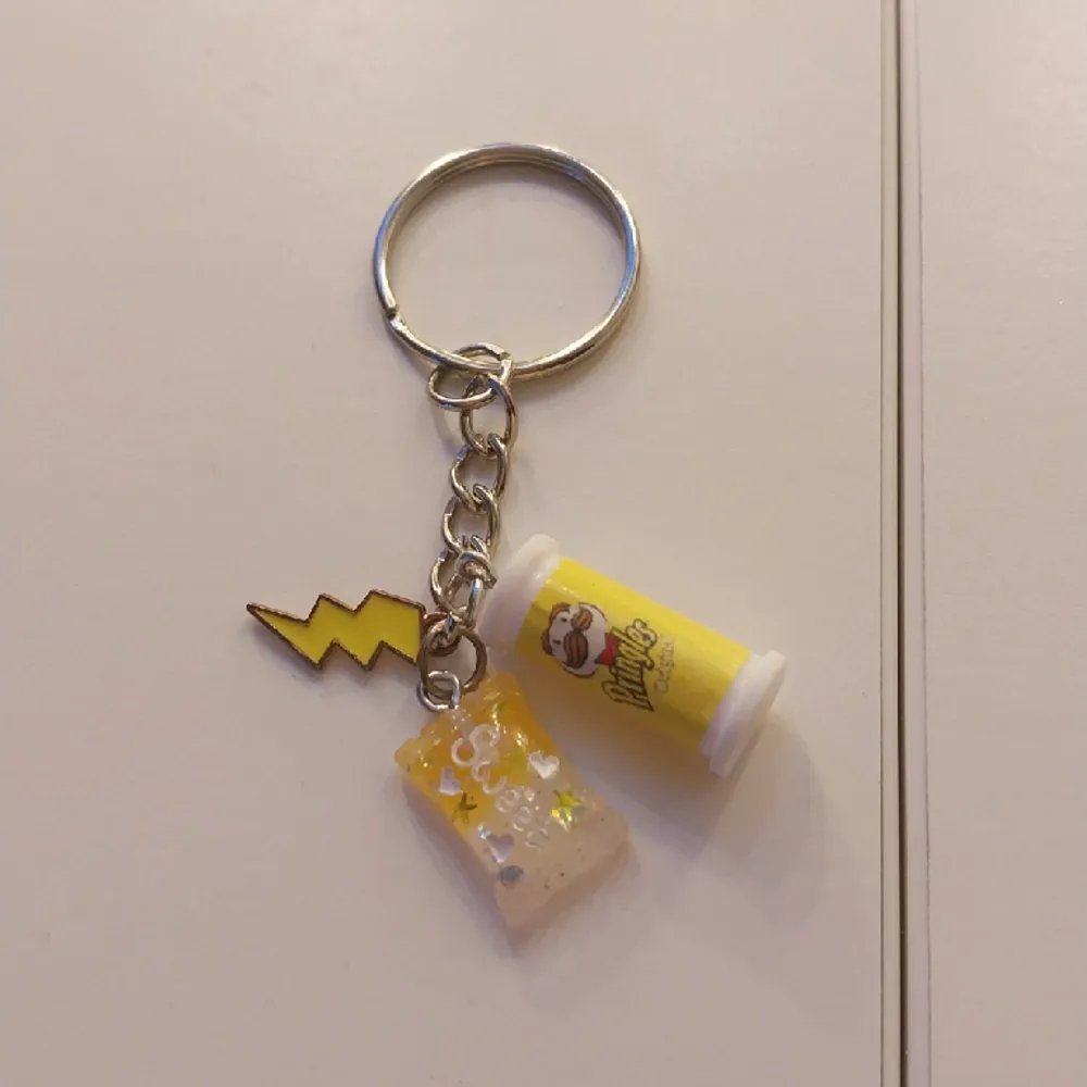 handgjord nyckelring med 3 berlocker på. Pringles, sweet godis och en gul blixt. . Accessoarer.