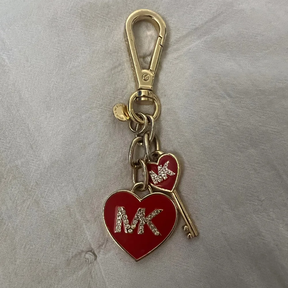 En nyckelring från MK i guld med röda synliga detaljer. Använd sparsamt och i ett väldigt bra skick, inga defekter.  Köpt i new york. Skriv för fler bilder🩷. Accessoarer.
