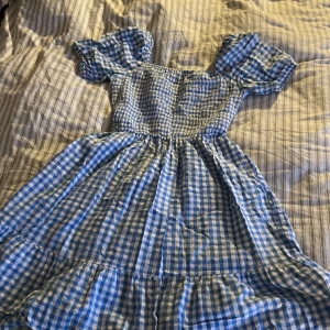 Blå/vit rutig sommar klänning - Ungefär ner till under dina knän. Öppen vid ryggen. Gjord för barn.