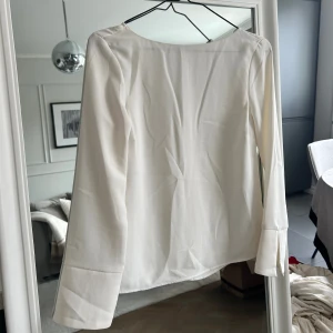 Vit blus - Blus i lite tjockare finare kvalité. Otroligt användbar. Fin design med knapp i nacken.