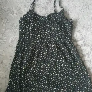 Blommig klänning med gula och rosa blommar, svart klänning. Storkel 38/M från H&M i mycket bra skick.  Har en smockad rygg och justerbara band