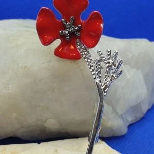 Brosch - Röd Vallmo (ny design) - Den här broschen föreställer en Vallmo och måtten är ca 7x 3.5cm. Silverfärgad metall med bl.a röd emaljering.  Snygg brosch i ny design.  Visa ditt stöd för de oskyldiga som dog under första världskriget genom att bära vallmo broschen.