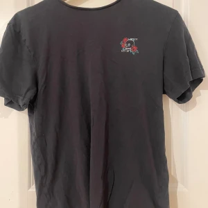 Svart t-shirt med dödskalle  - Cool svart t-shirt med dödskalle och rosor. Inga defekter 