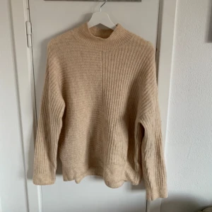Stickad tröja - Beige stickad tröja med randigt material. Näst intill oanvänd 